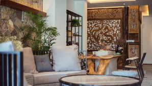 A cozy living area with a sofa, round tables, and chairs, surrounded by plants and decorative elements. - Li River Resort (Guilin)