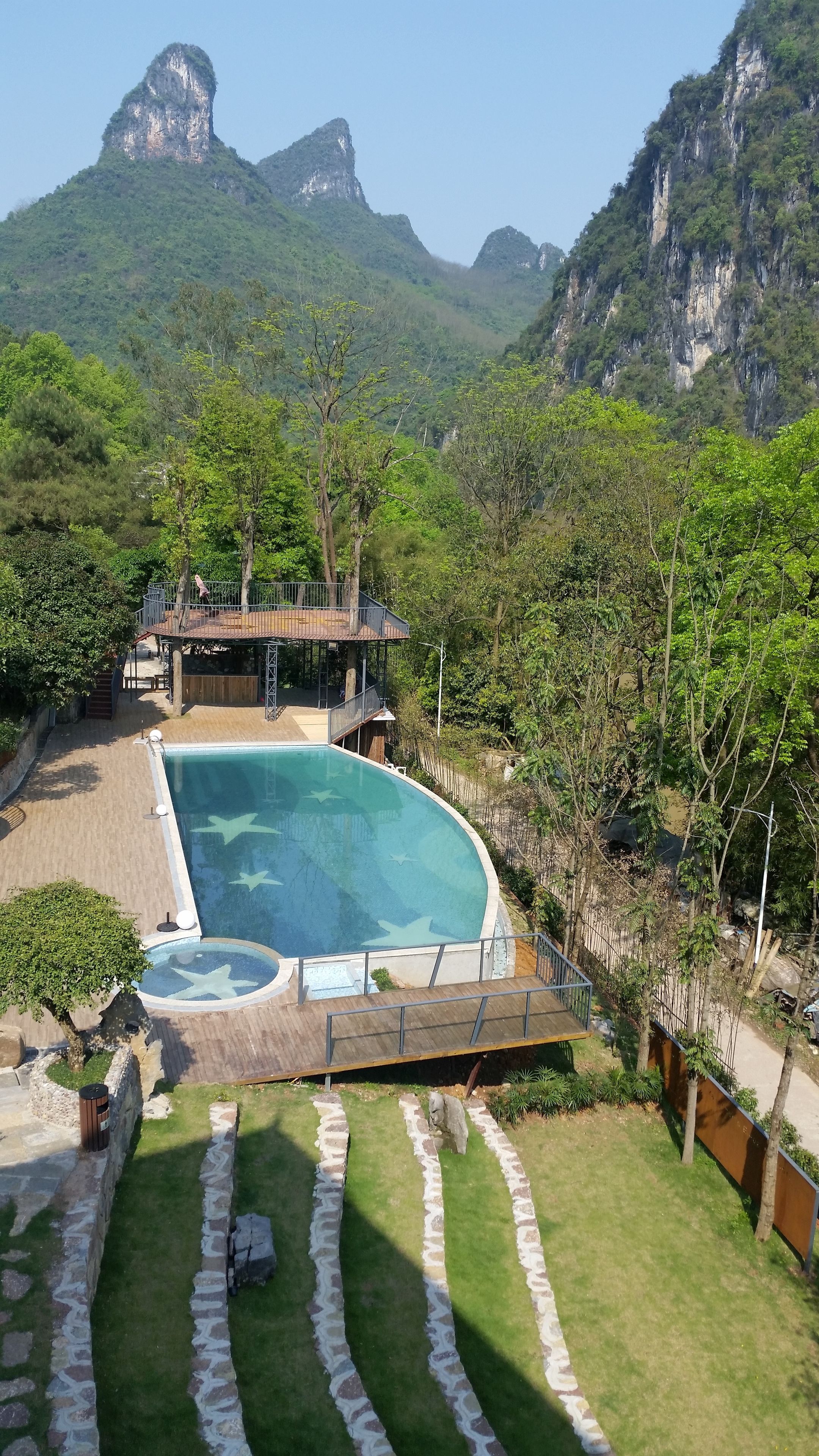 A swimming pool with a deck, surrounded by a well-maintained lawn and stone edging.