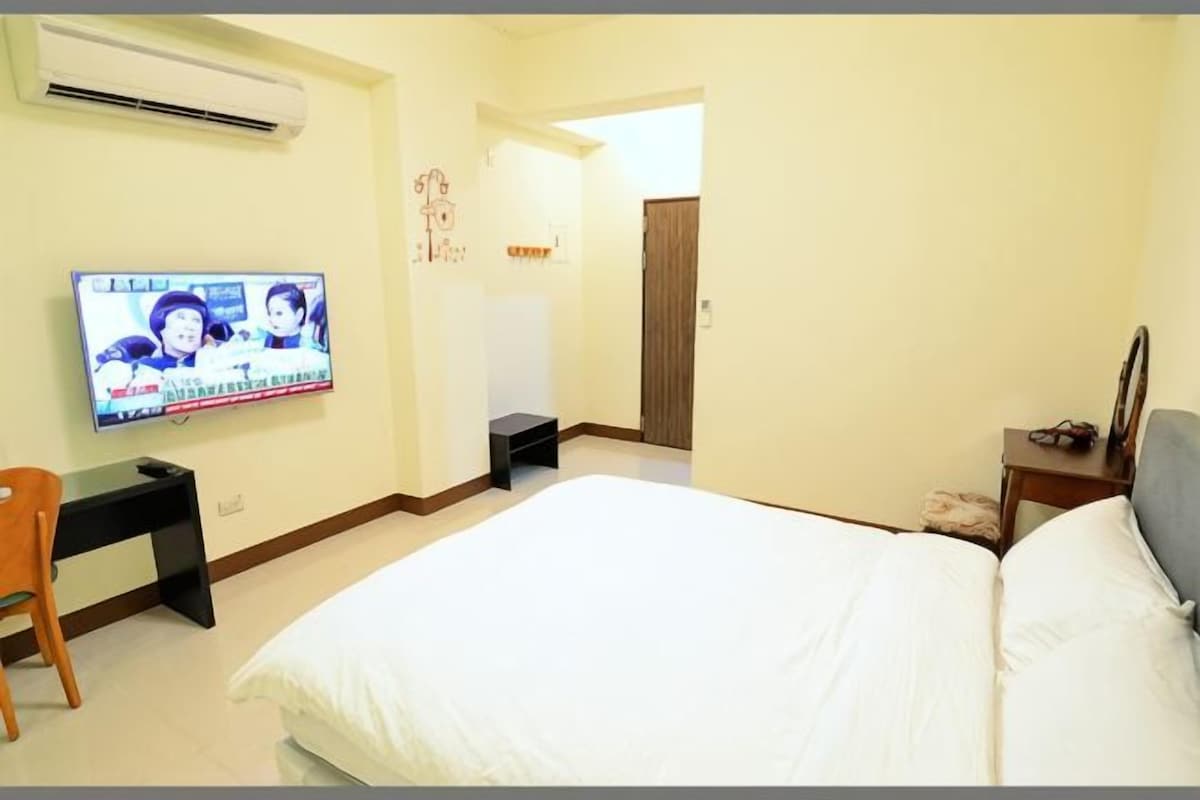 Una habitación de hotel con una cama, un televisor, un escritorio y una silla.