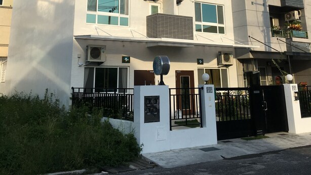 Un edificio moderno de varios pisos con balcones, unidades de aire acondicionado y una entrada con portón.