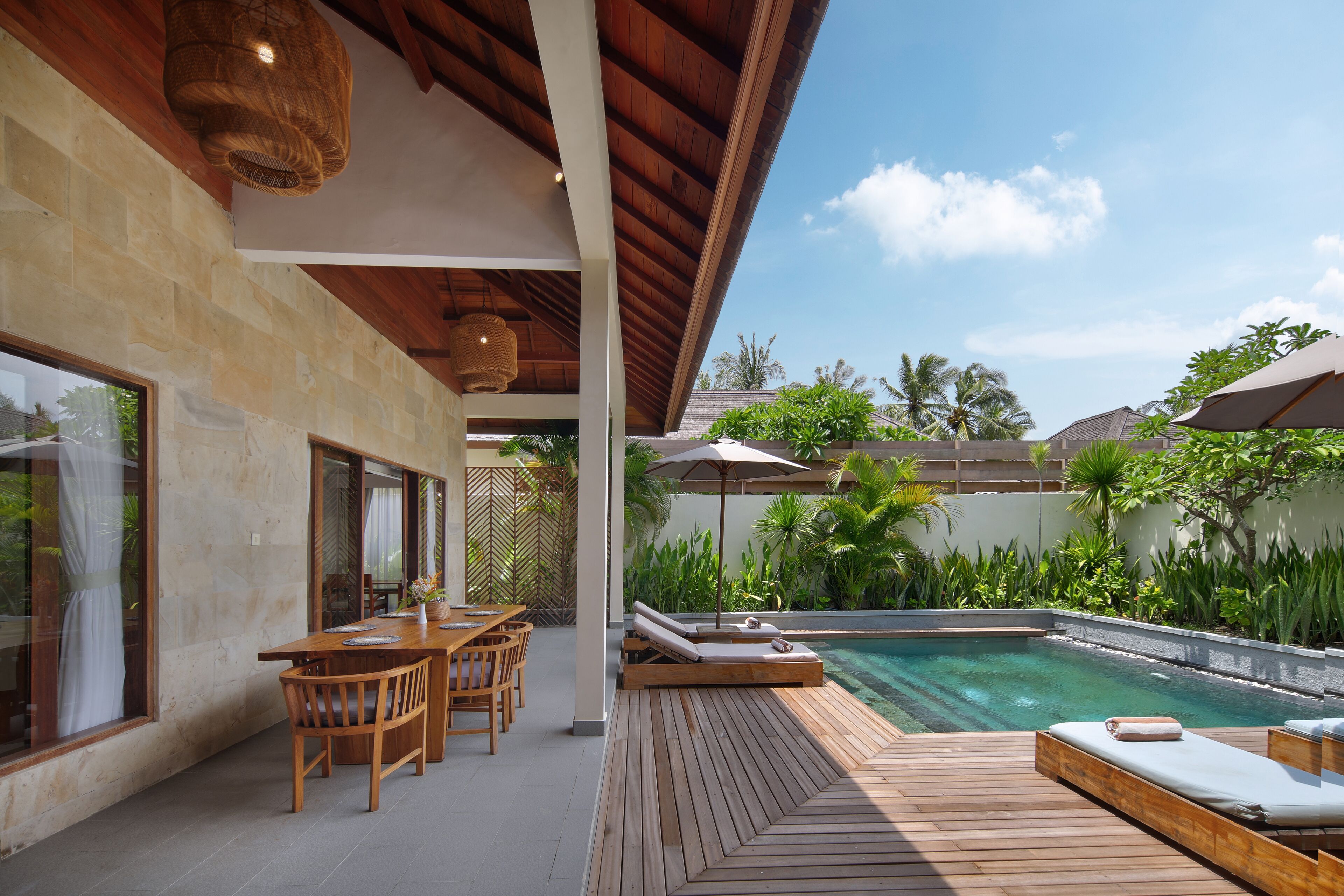 A wooden deck with a pool, outdoor seating, and a view of the surrounding greenery.