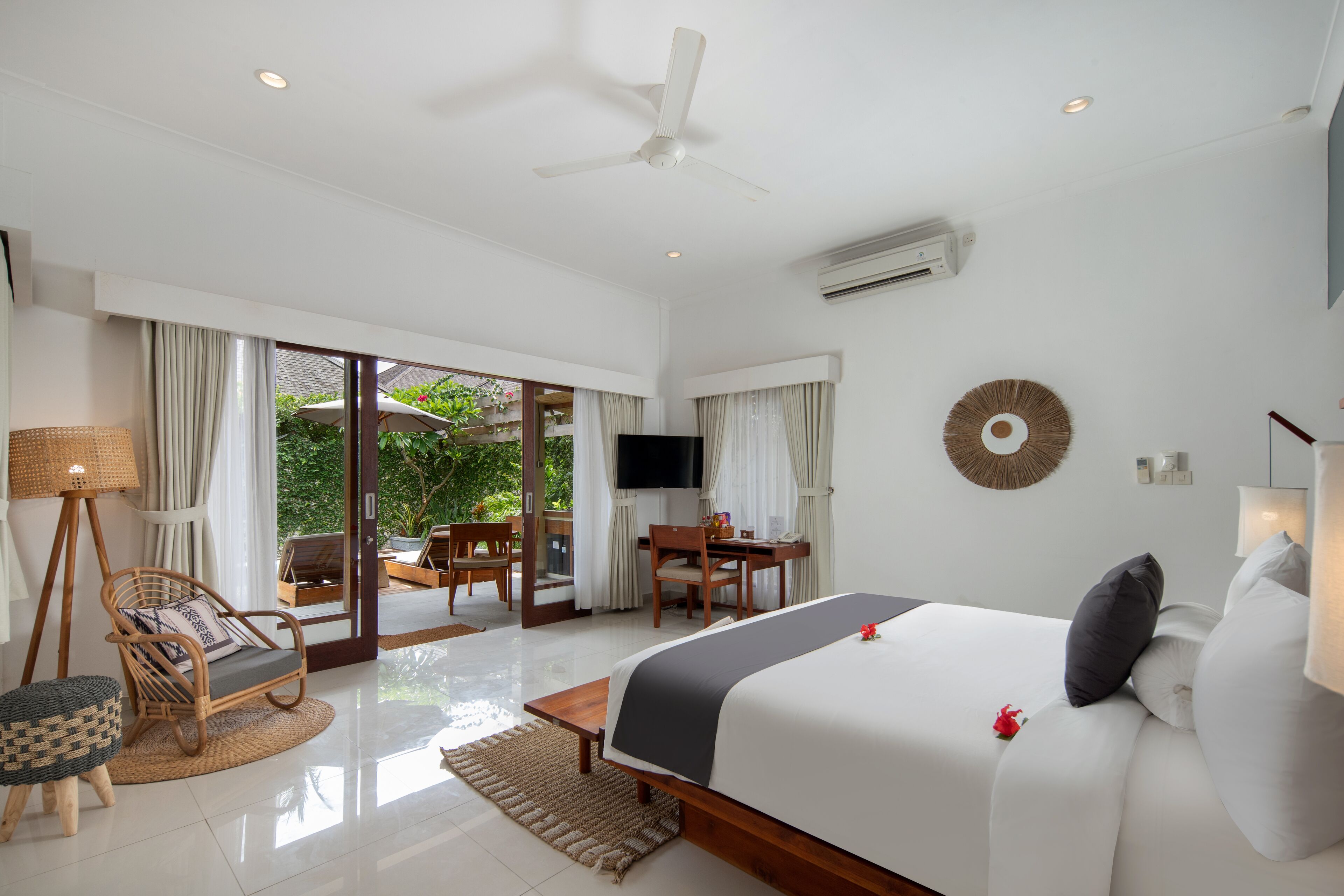 A hotel room with a bed, a desk, a chair, a television, and a view of the outdoors.
