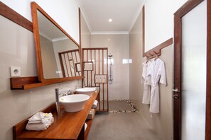 Un baño moderno con tocador de madera, dos lavamanos, un espejo grande y zona de ducha.