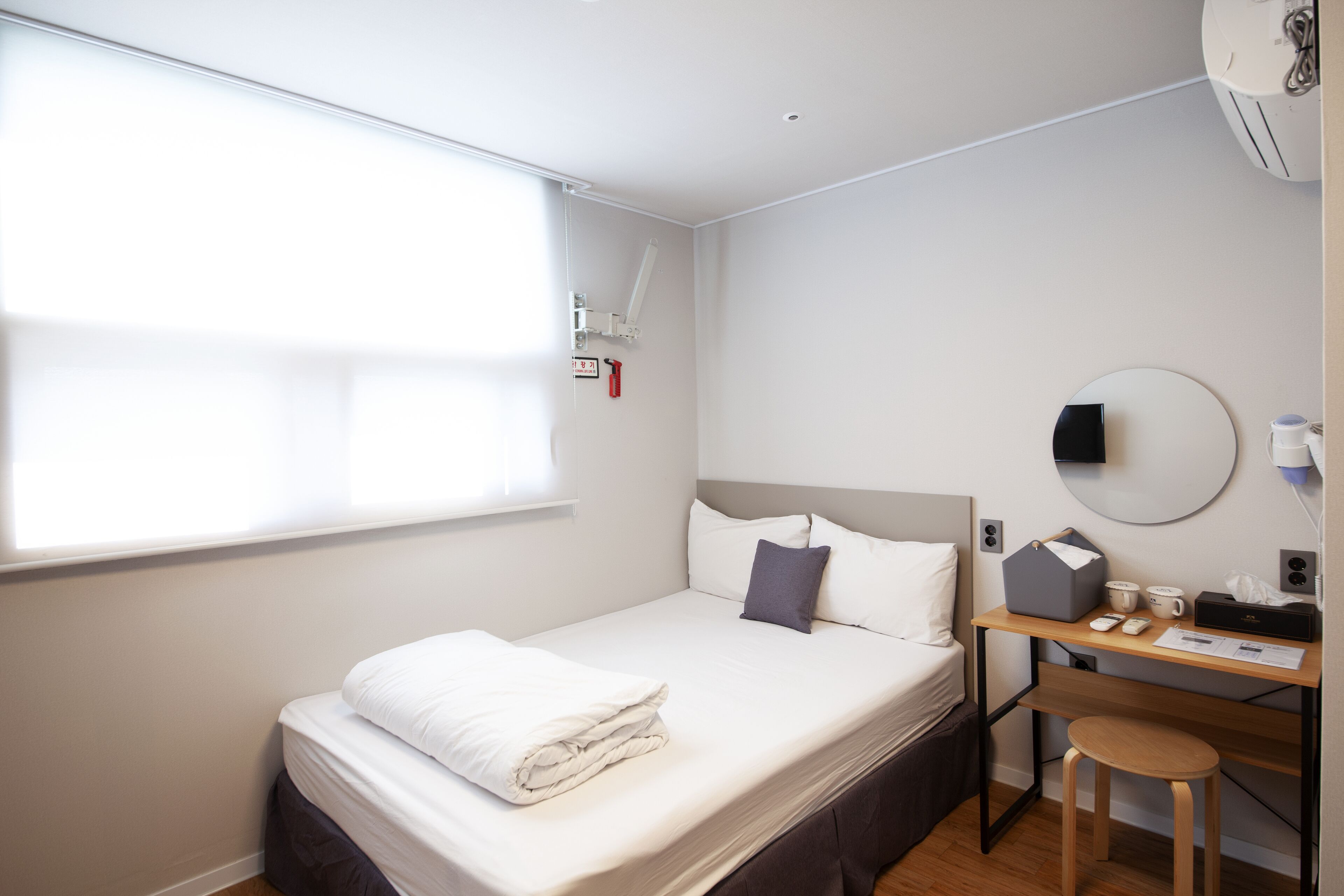 Ein ordentlich eingerichtetes Hotelzimmer mit Bett, Schreibtisch und Stuhl.