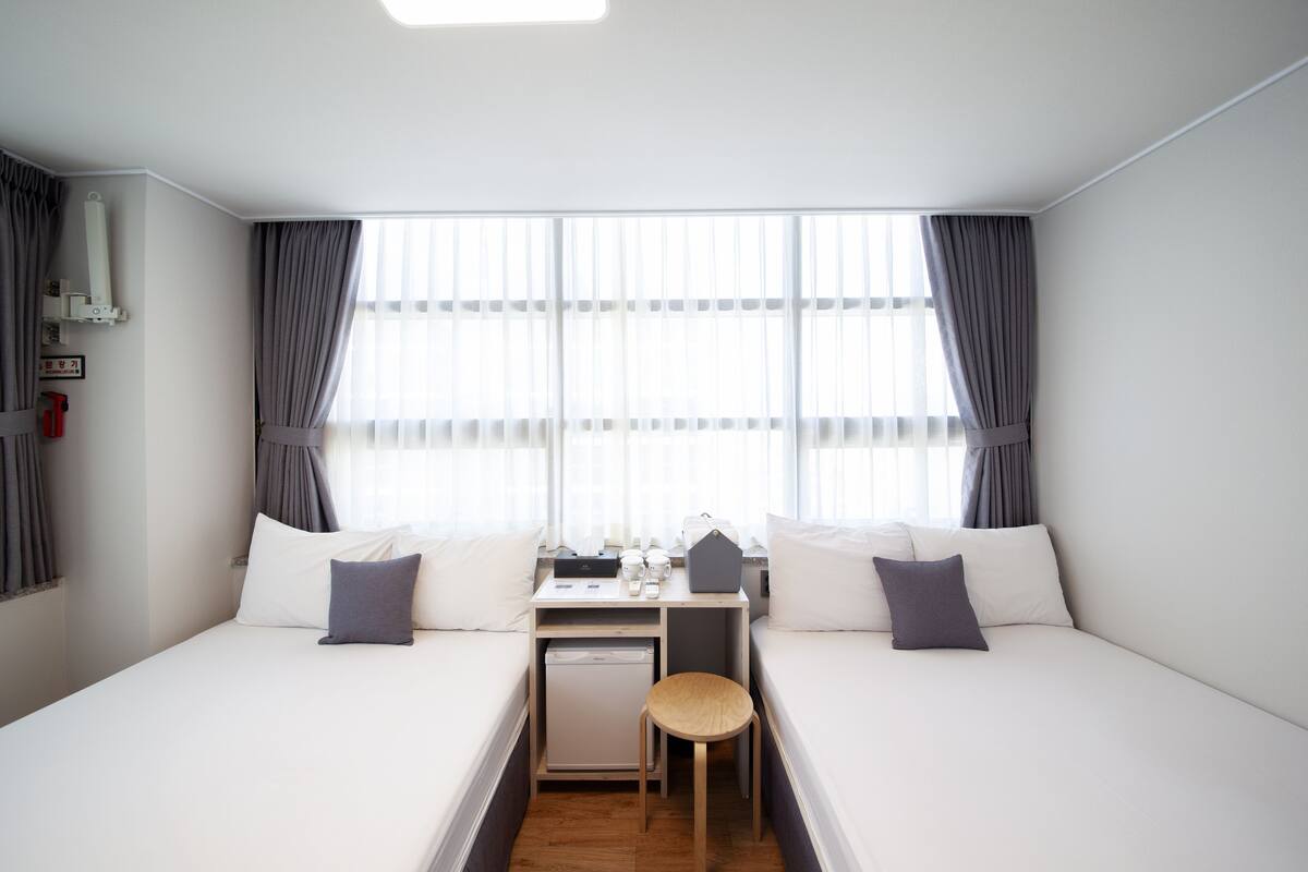 Habitación de hotel con dos camas, un escritorio y una silla pequeña.
