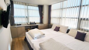 A hotel room with a large bed, a desk with a computer, and a window with curtains. - K- Grand Hostel Dongdaemun (Seoul)