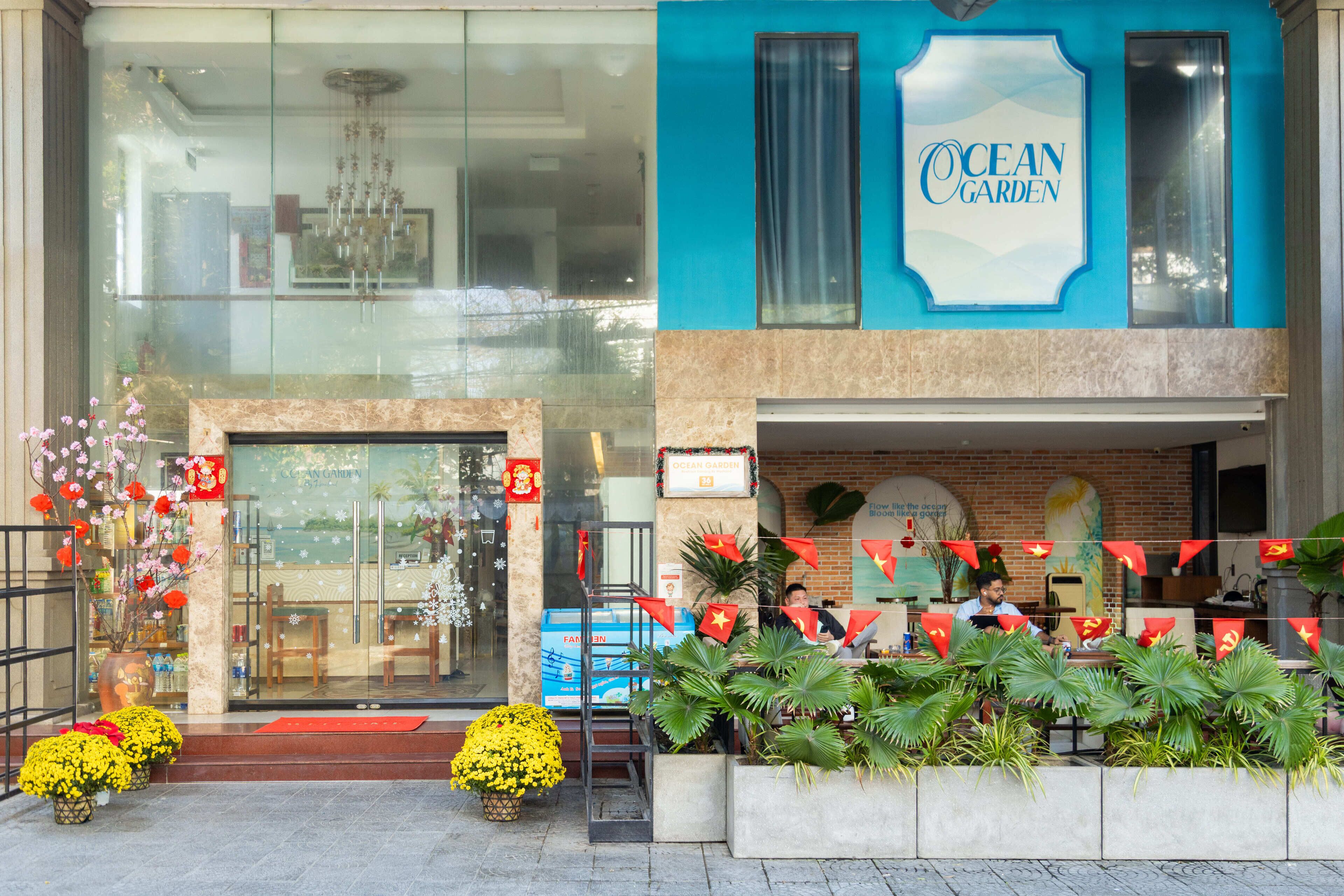 A hotel entrance with a sign reading "Ocean Garden," a glass facade, and a brick wall.