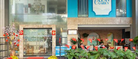 A hotel entrance with a sign reading "Ocean Garden," a glass facade, and a brick wall.