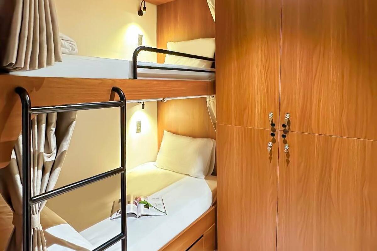 Une petite chambre comprenant un lit superposé, une armoire en bois et une petite table de chevet.
