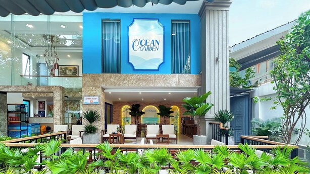 Un vestíbulo de hotel con un llamativo letrero que dice 'Ocean Garden', zonas de estar y vistas del edificio contiguo.