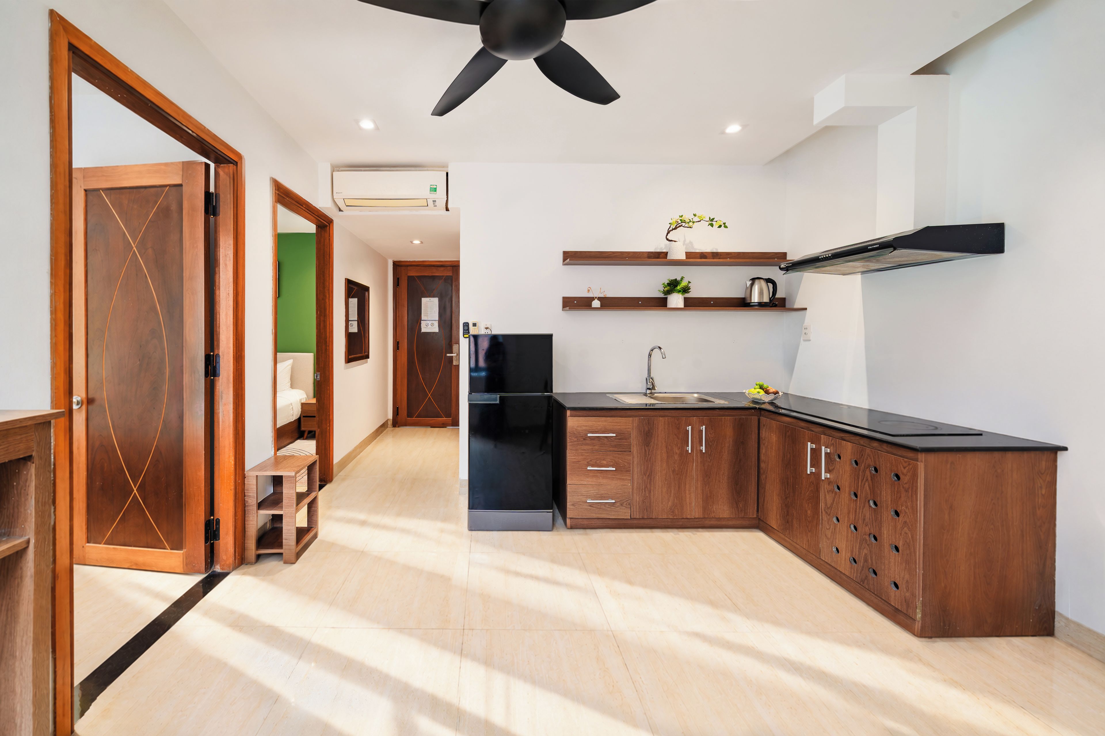 A modern kitchen with wooden cabinets, a black countertop, and a ceiling fan.