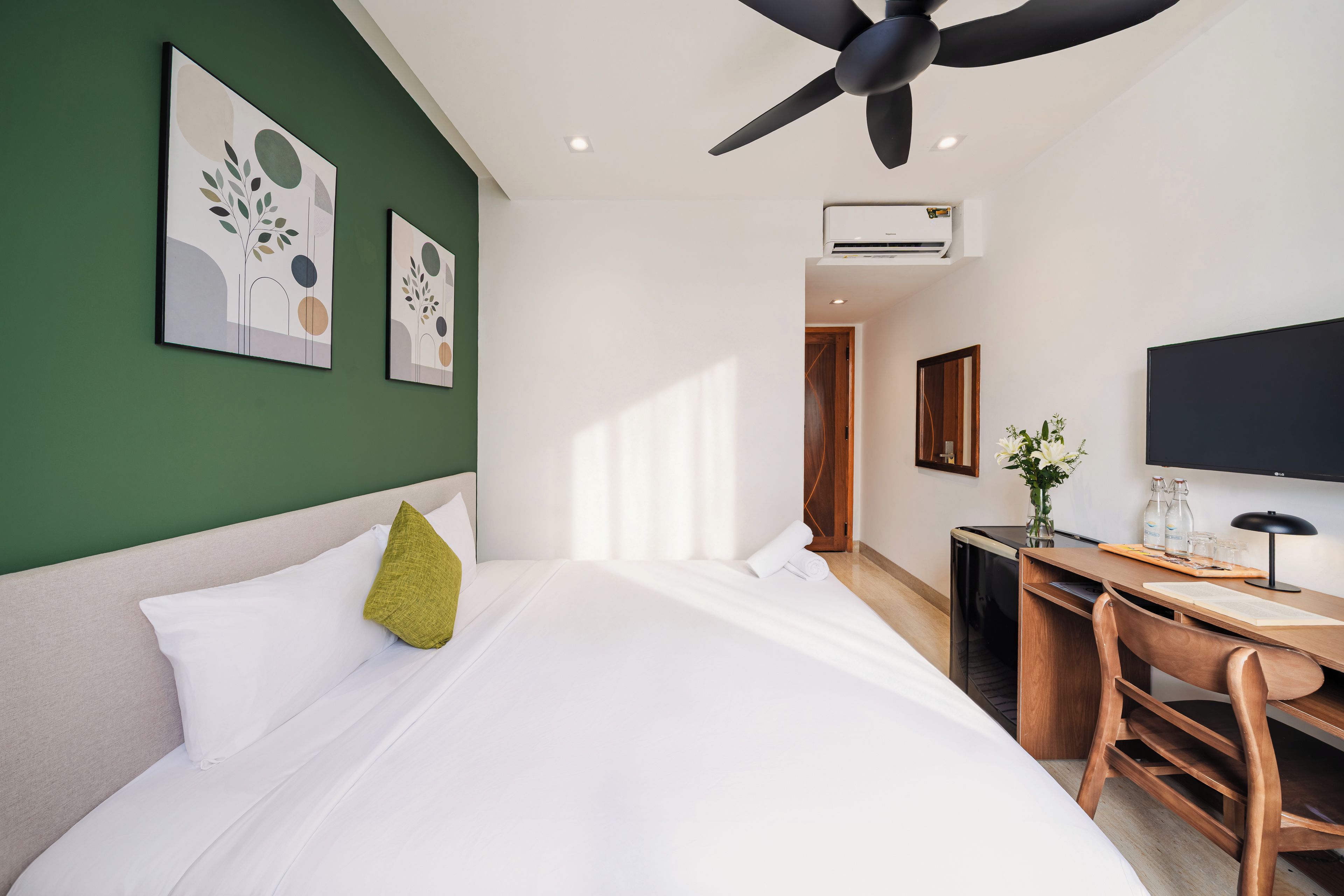Ein Hotelzimmer mit Bett, Schreibtisch, Sessel, Fernseher und Bildern an den Wänden.