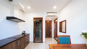 Una cocina moderna con encimera negra, armarios de madera y una puerta abierta que da al baño.