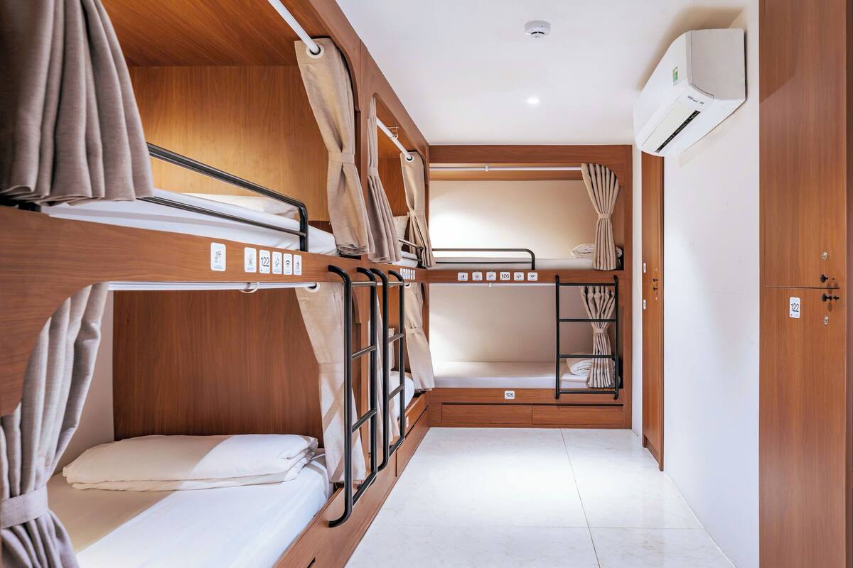 Une pièce compacte et bien éclairée, avec des lits superposés, des murs en bois et une petite armoire.