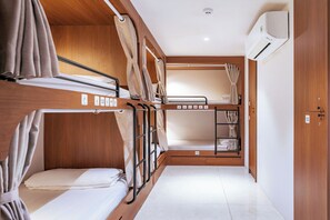Een compacte, goed verlichte kamer met stapelbedden, houten wanden en een kleine garderobe.