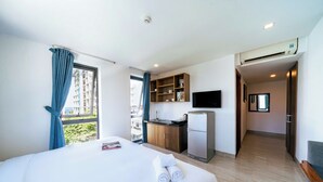 Habitación de hotel con cama, kitchenette, televisor y vistas a la ciudad.