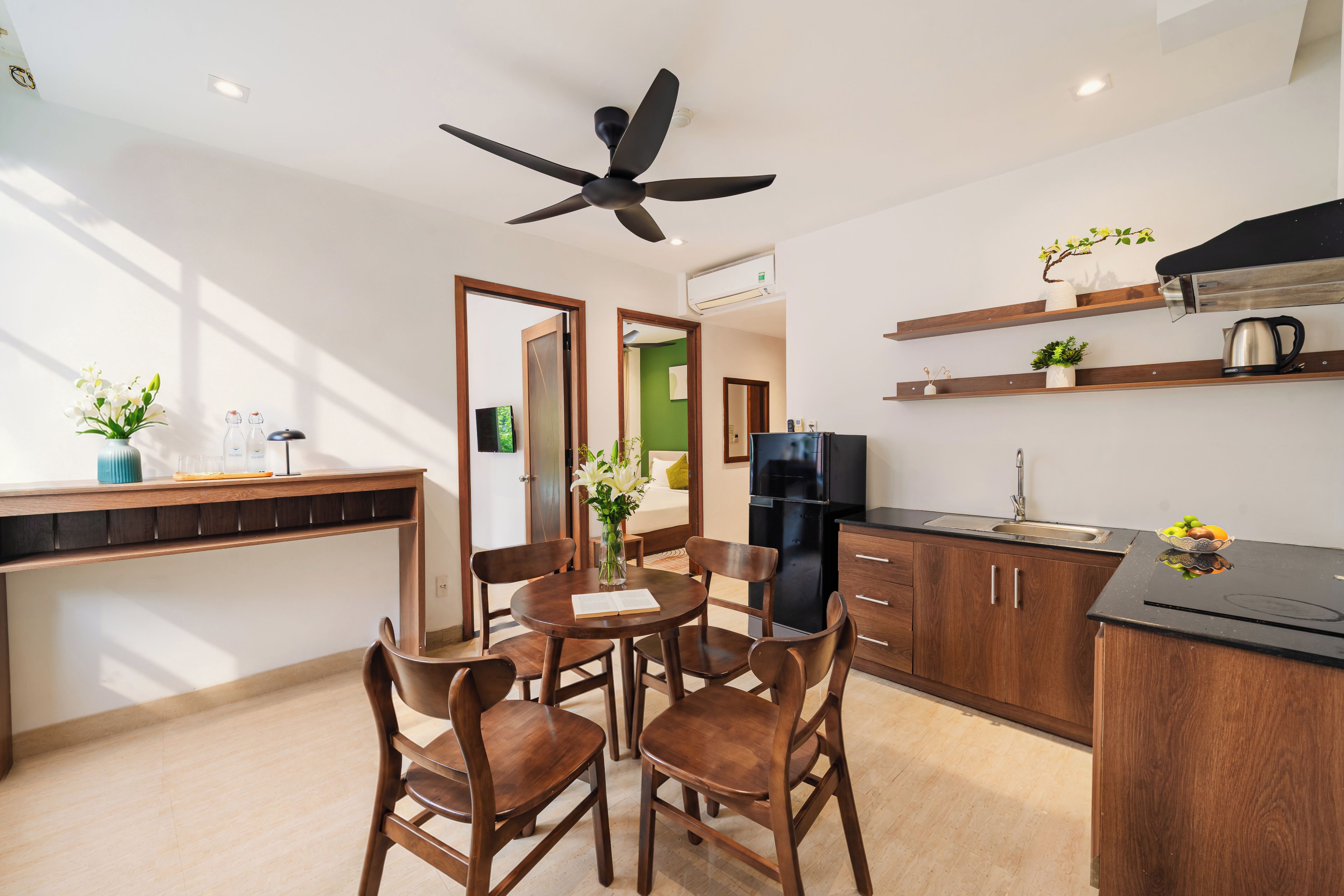 Una cocina moderna con armarios de madera, un refrigerador negro y una mesa de comedor con sillas.