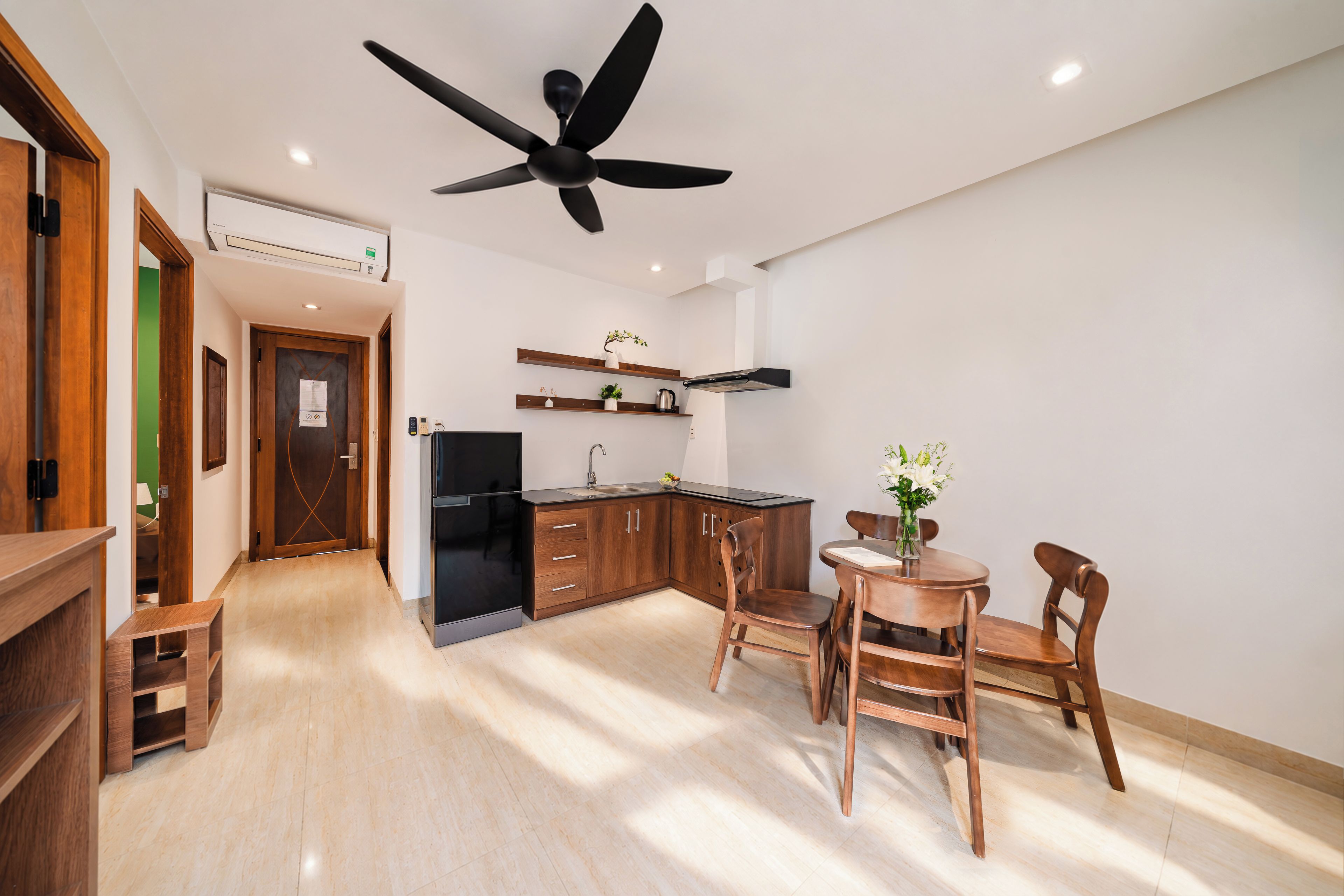 Una cocina moderna con armarios de madera, un refrigerador negro y un ventilador de techo.