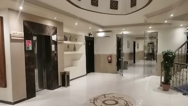 Un hall d’hôtel doté d’un motif circulaire central sur le sol, d’un escalier et d’un extincteur fixé au mur.