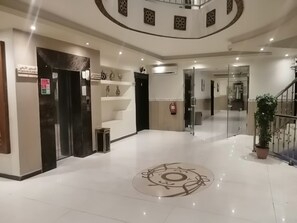 Un vestíbulo de hotel con un diseño circular en el suelo, una escalera y un extintor en la pared.