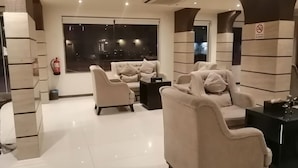 Un espace de détente moderne avec des canapés, un extincteur et une vue sur la ville la nuit.