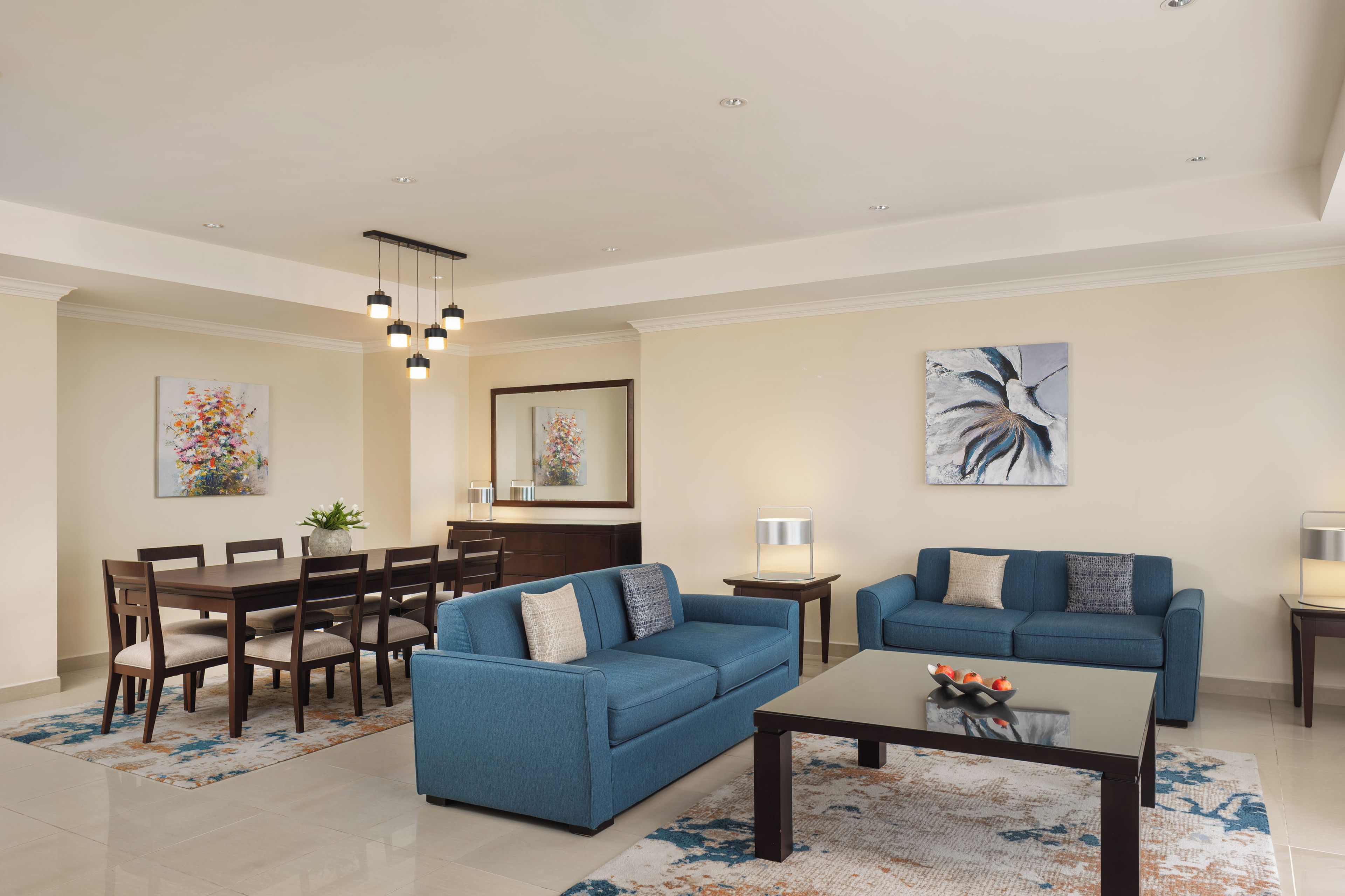 Uma sala de estar moderna com um sofá azul, uma mesa de centro e um espaço de jantar com mesa e cadeiras de madeira.
