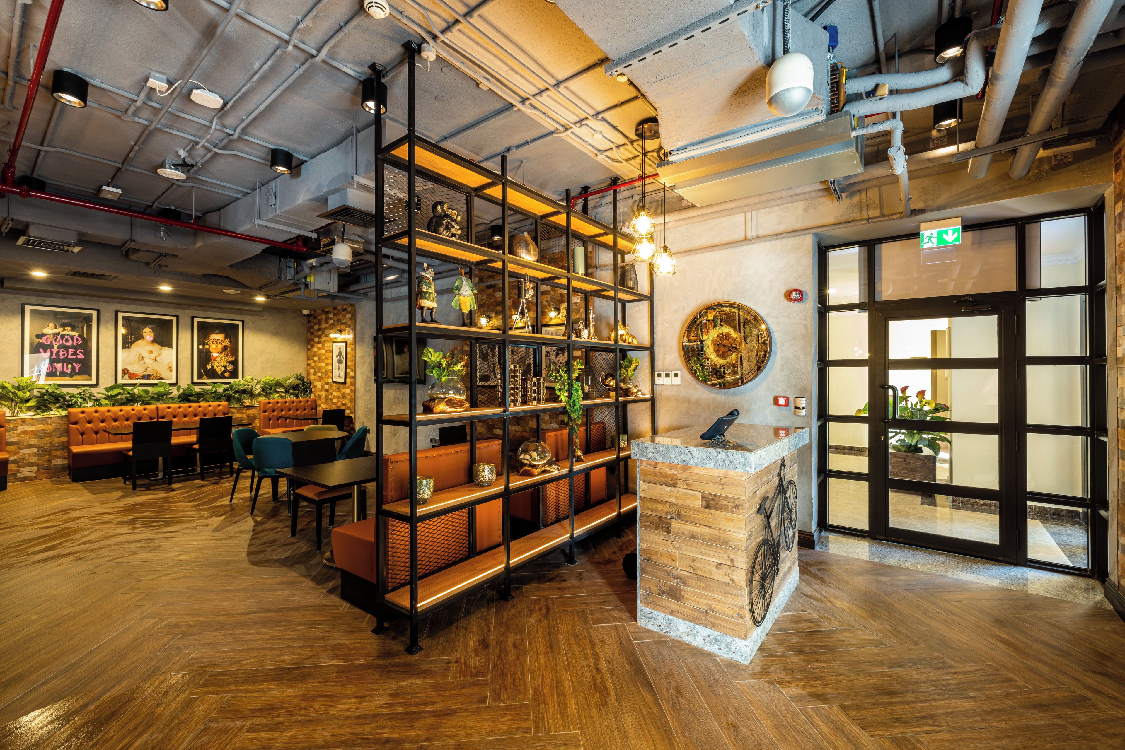 Interior de un restaurante con suelo de madera, una zona de bar y un área de mesas y cabinas con cojines.