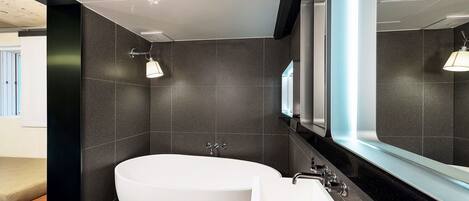 Une salle de bain moderne avec une baignoire sur pieds, un lavabo blanc et un grand miroir.