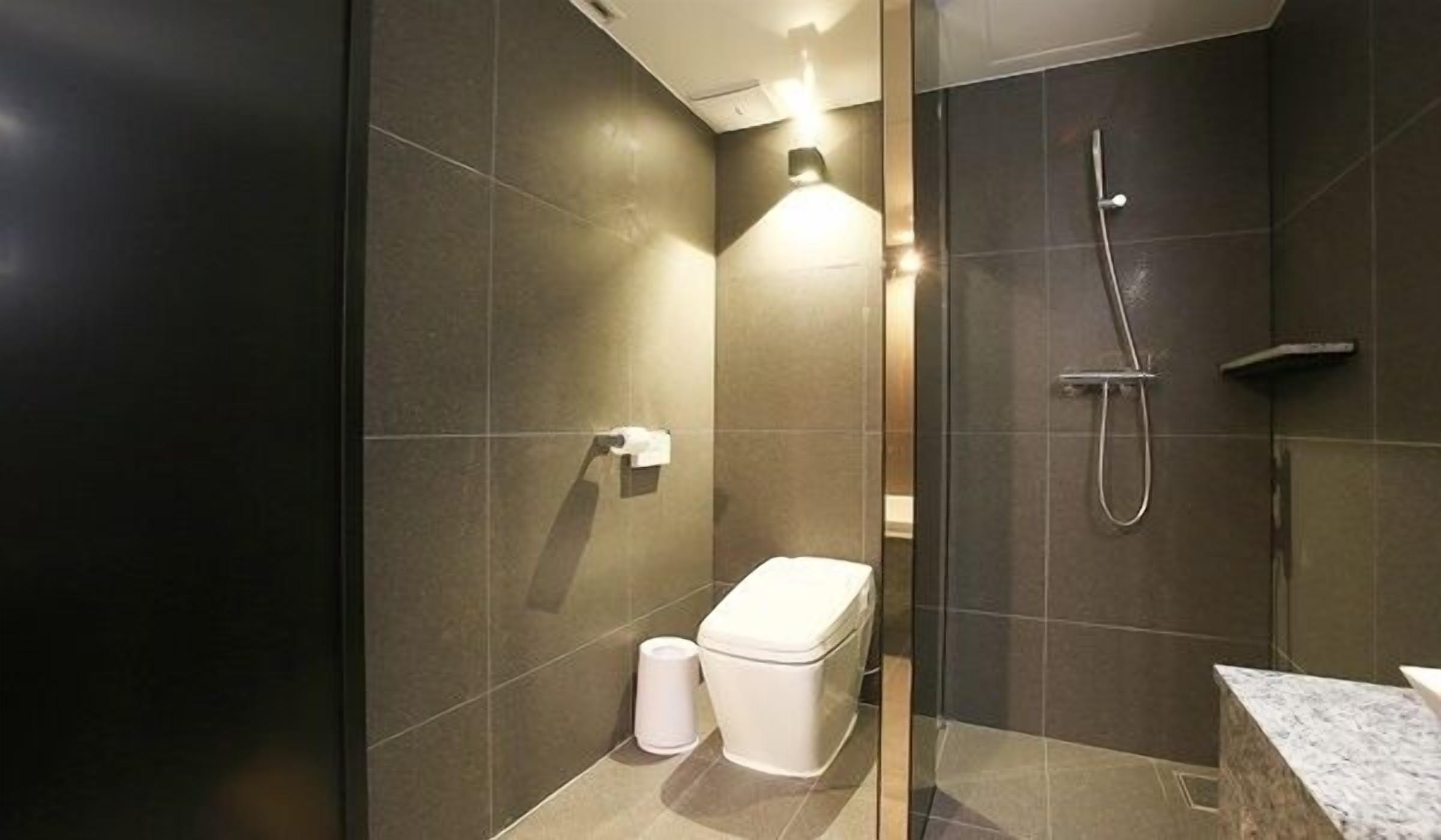 A modern bathroom with a glass shower enclosure, a toilet, and a marble countertop.