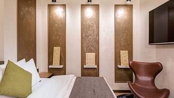 Ein Hotelzimmer mit einem Bett, einem braunen Stuhl und drei beleuchteten Vertikalpaneelen.