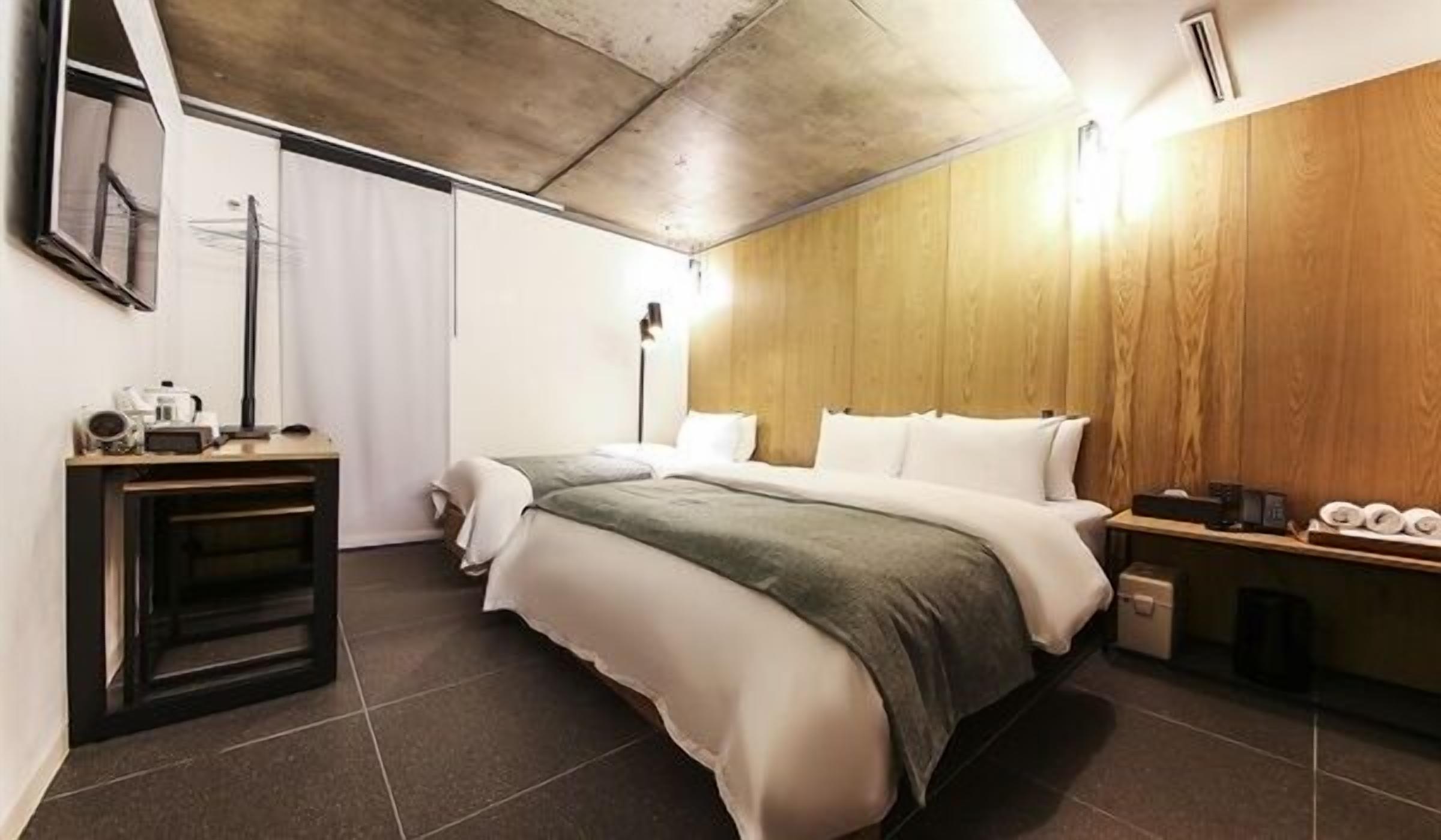 Una habitación de hotel moderna con una cama grande, un escritorio pequeño y una pared decorativa de madera.