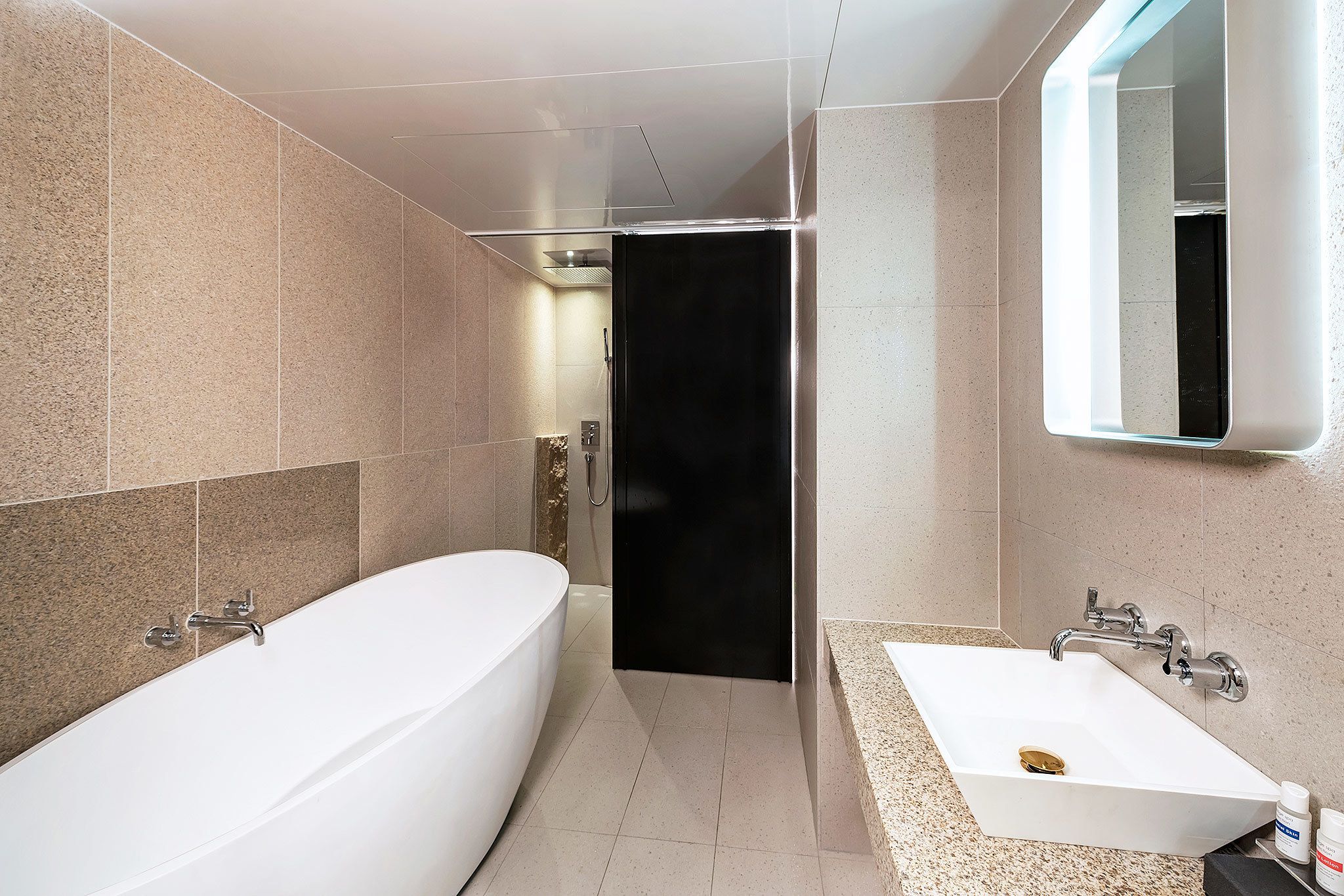 A modern bathroom with a large bathtub, a separate shower area, and a vanity with a sink.
