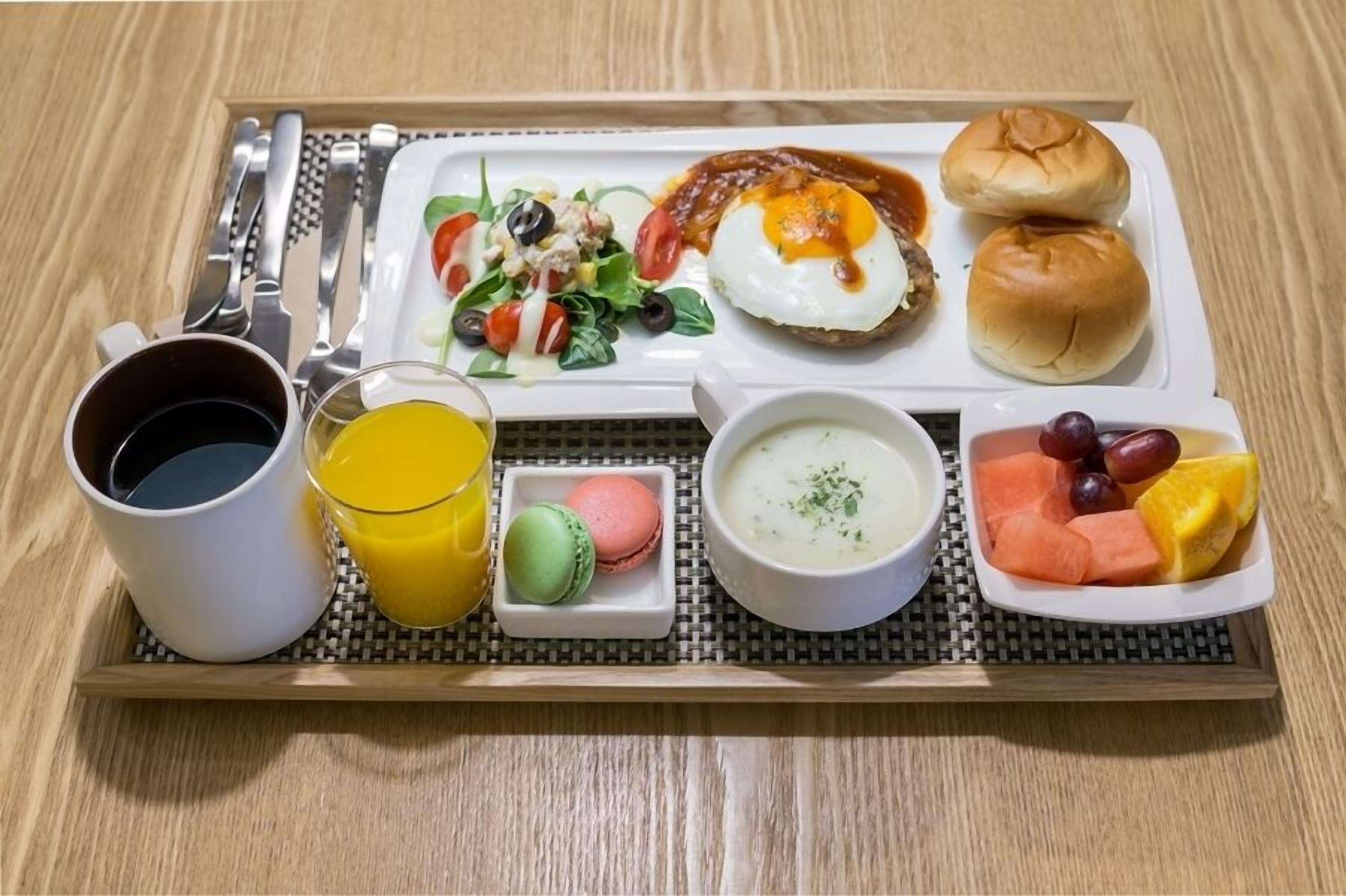 A tray with a variety of breakfast items including eggs, toast, salad, fruit, and beverages.