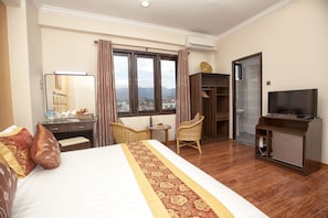 A hotel room with a bed, a desk, a chair, a television, and a wardrobe. - The Hotel Emperor Inle (Nyaungshwe)