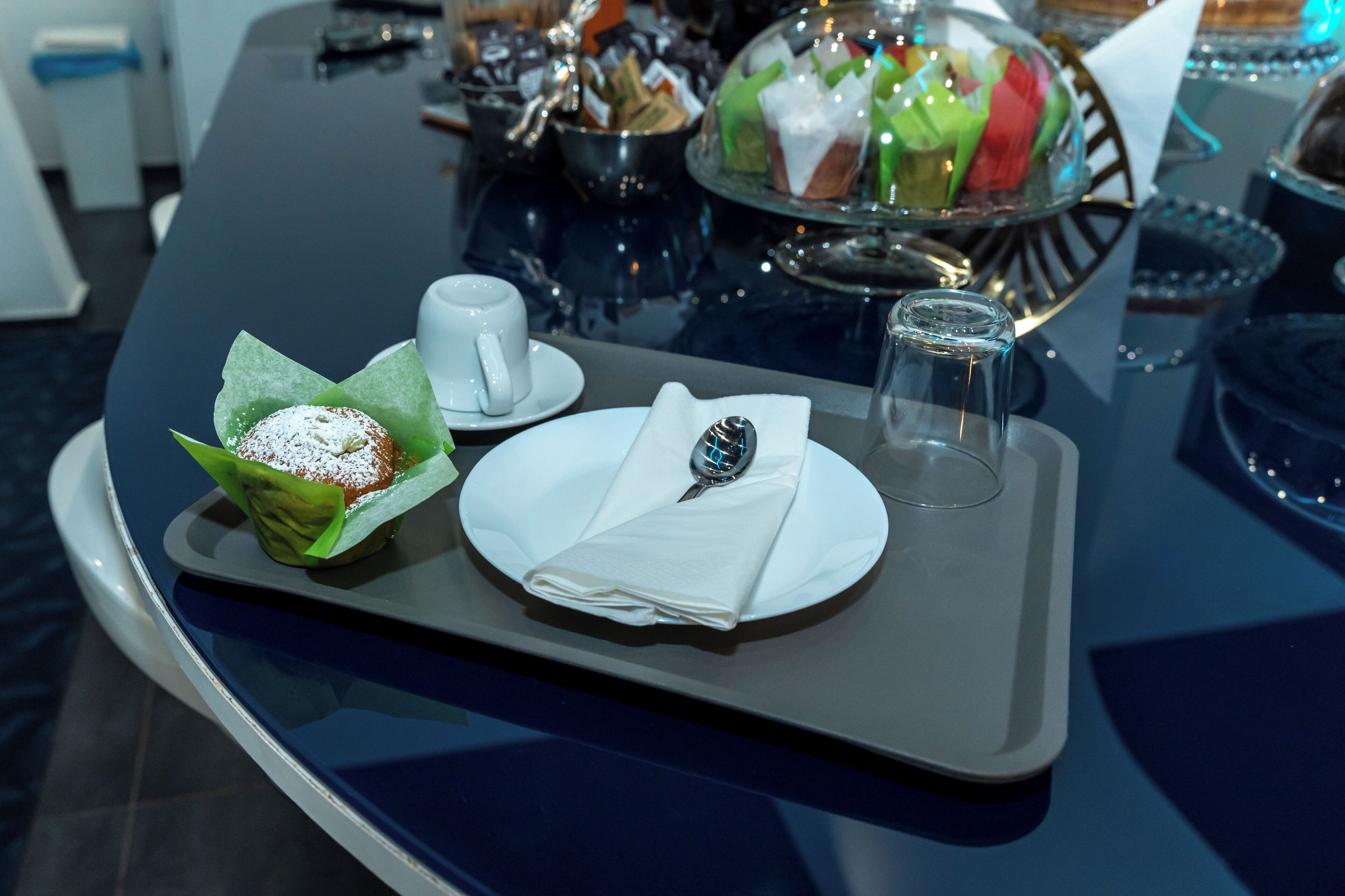 Una bandeja con un postre, una taza y una cuchara sobre una mesa.