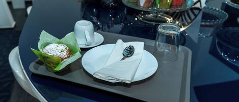 A tray with a dessert, a cup, and a spoon on a table.