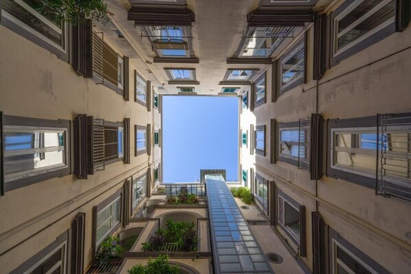 A narrow corridor with multiple windows and balconies, leading to a clear sky. - B&B Skyhouse Chiaia  (Naples)