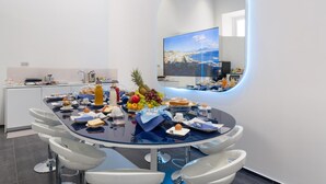 Una cucina moderna con un tavolo da pranzo rotondo, sedie bianche e un'isola grande.