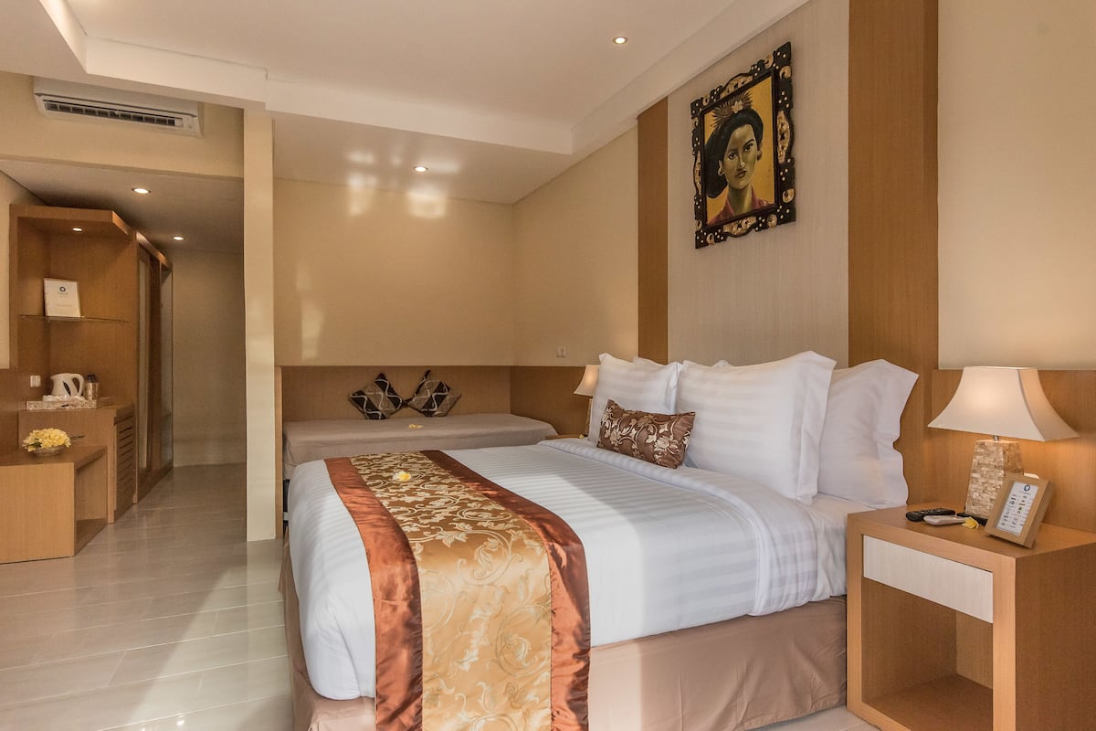 A hotel room with a large bed, a bedside table with a lamp, a small desk with a telephone, and a picture frame on the wall.