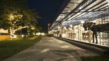 A covered outdoor area with a horse statue, a pathway, and a building with a glass roof.