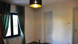 Une pièce dotée d’une grande fenêtre, d’un radiateur, d’une porte et d’une barrière en métal noir.