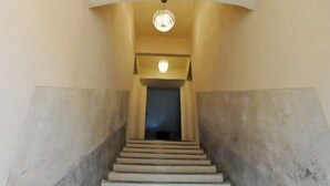 Un escalier avec un luminaire au-dessus et une porte en haut.