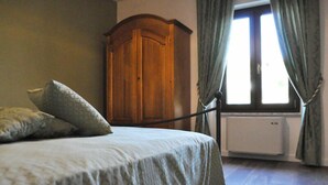 Une chambre à coucher avec un lit, une armoire en bois et une fenêtre avec des rideaux.