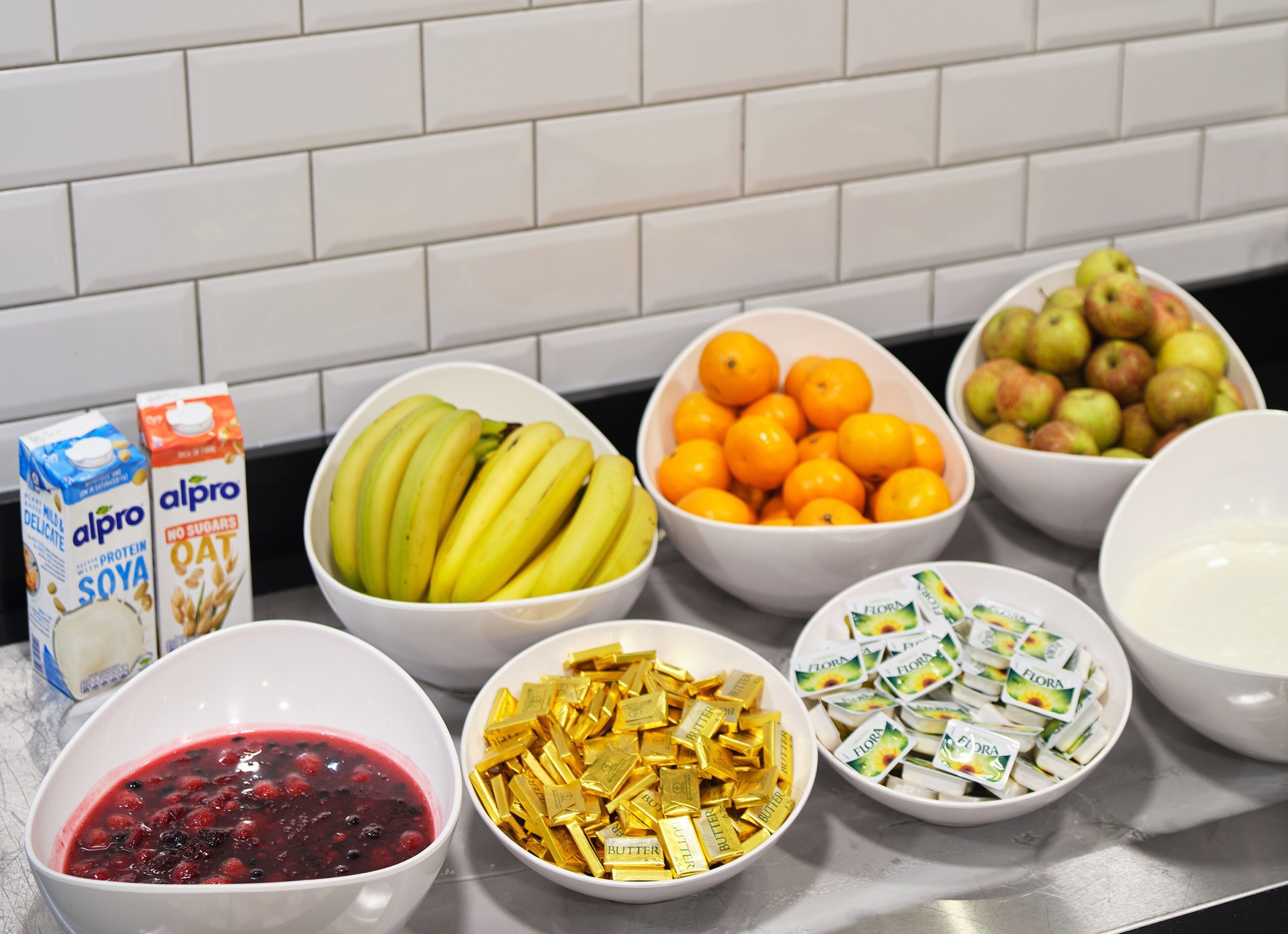 En køkkenbordplade med forskellige spisemæssige ting, herunder bananer, appelsiner, æbler og bær.