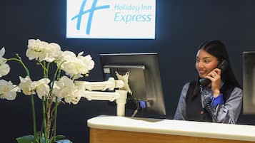 Een receptiebalie van Holiday Inn Express met een bordje, een computermonitor en een potorkidee.
