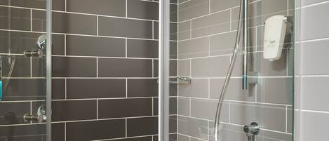 Een moderne douche met een glazen cabine, een handdouche en een extra douchestraal.