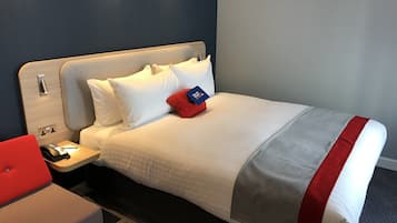 Ein Hotelzimmer mit einem Bett, einem Nachttisch, einem roten Sessel und einem Holztisch.