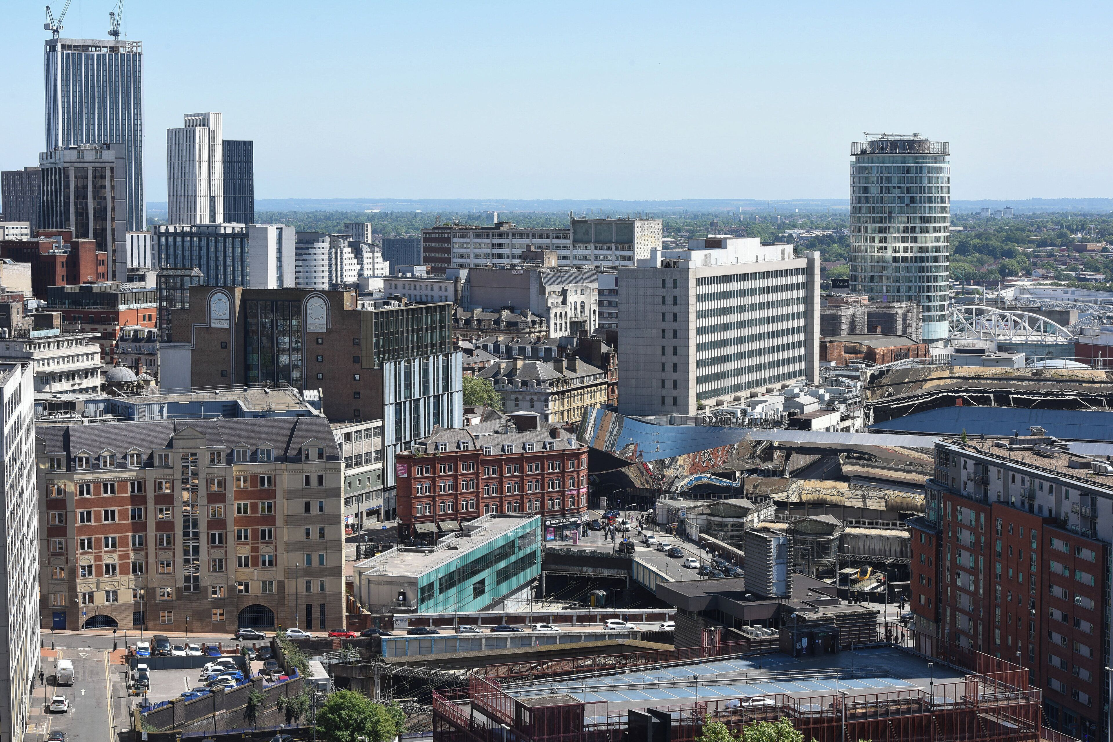 A cityscape with various buildings, including a prominent red brick building and a modern glass skyscraper.