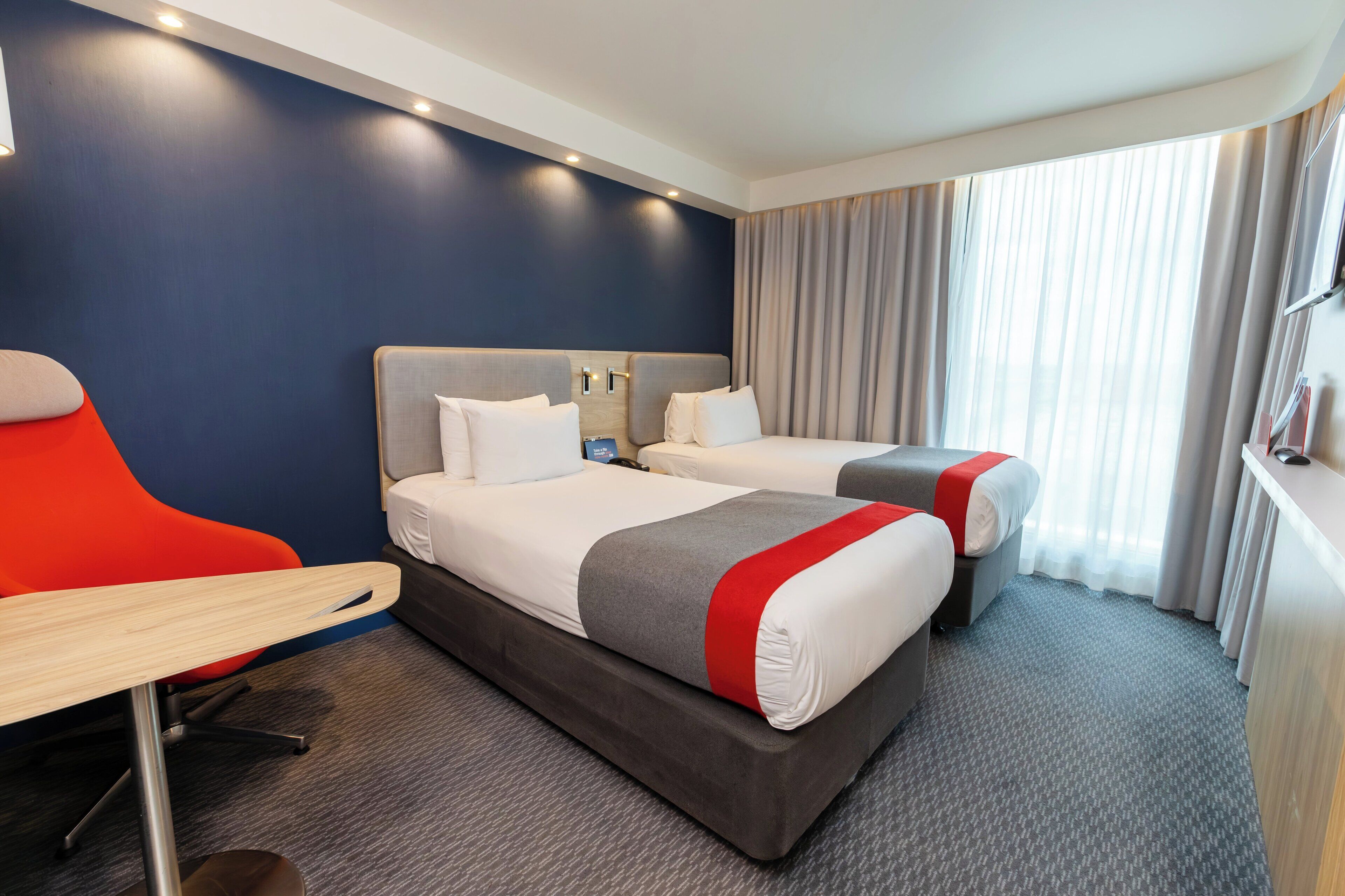 Habitación de hotel con dos camas, un escritorio y una silla.