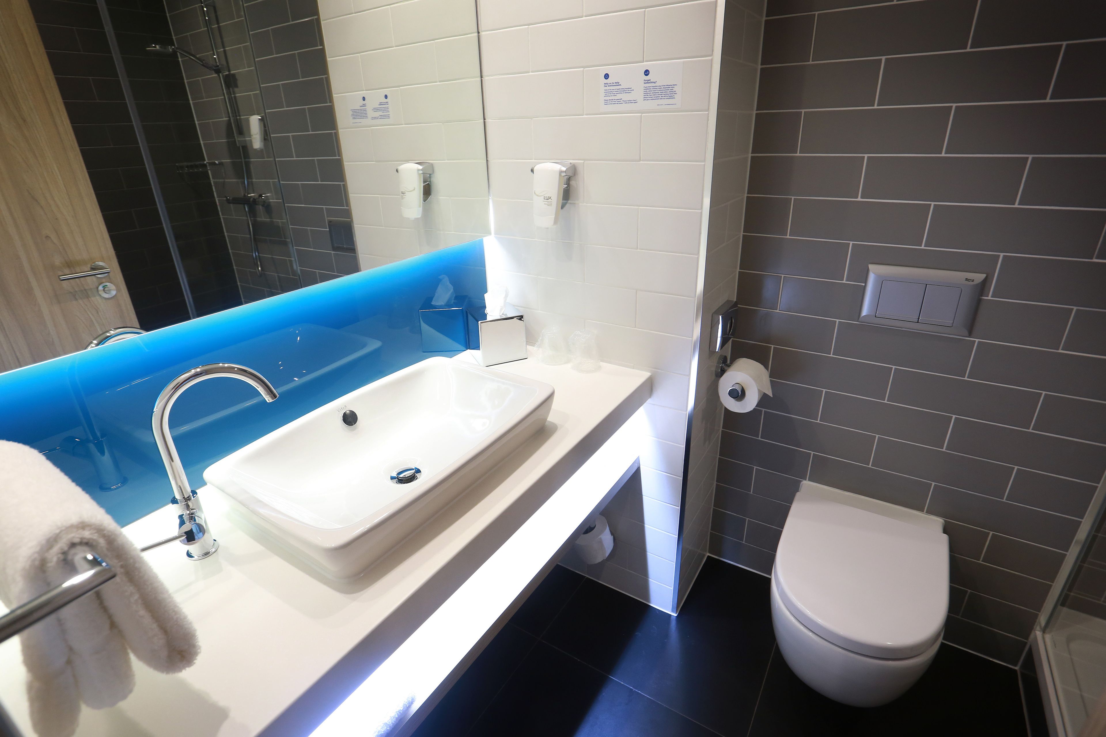 A modern bathroom with a white sink, a glass shower enclosure, and a white toilet.